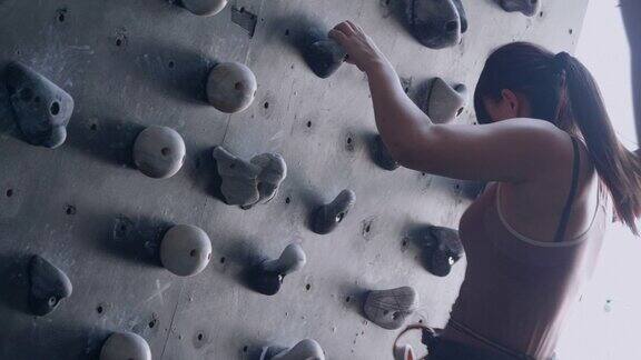 亚洲妇女训练攀登者抱石人造墙