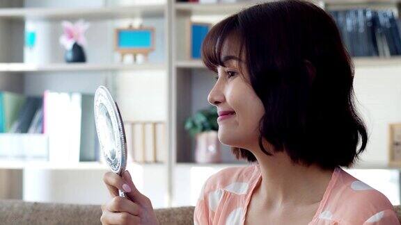 快乐微笑的亚洲年轻女子看着镜子