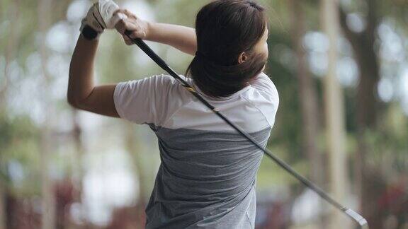 亚裔华裔女高尔夫球手在练习场练习挥杆