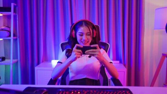 亚洲美女电竞女玩家在智能手机上玩手机游戏有吸引力的年轻女孩游戏玩家感到快乐享受技术直播而在家里玩网络比赛