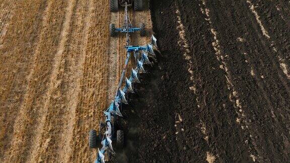 红色的大拖拉机开在橡胶履带上在田地里拉着多产的反耕犁为种植新作物准备土壤农业拖拉机田间耕作的鸟瞰图慢动作视频