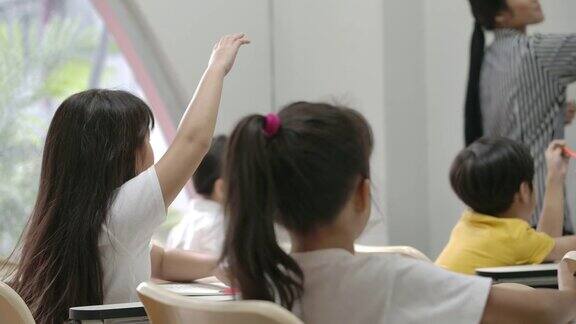 亚洲小女孩举手回答老师提问的背影幼儿园学前概念