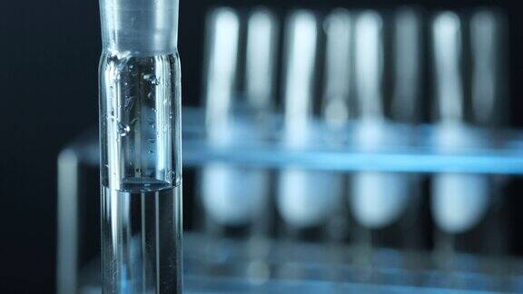 科学家把化学溶液滴在试管里在黑色背景上混合做实验室实验蓝色的光化学和医学概念