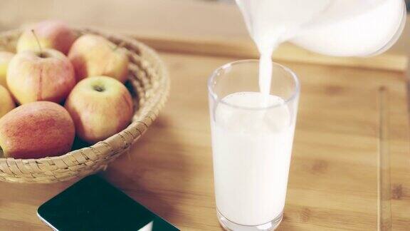 把牛奶倒进桌子上的杯子里
