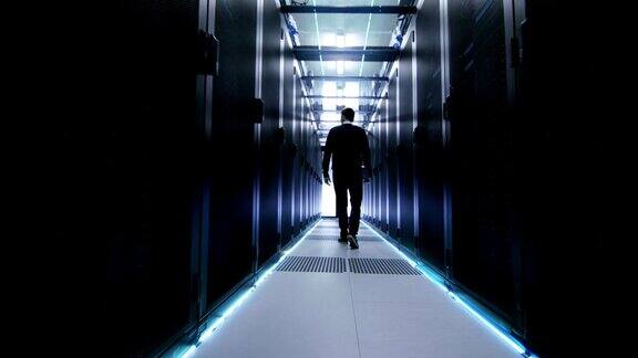 以下是IT工程师与一排排机架服务器穿过数据中心走廊的照片