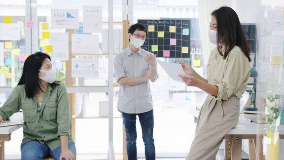 亚洲商务人士在新常态的办公室里开会头脑风暴进行商业演示想法项目同事并戴上防护口罩