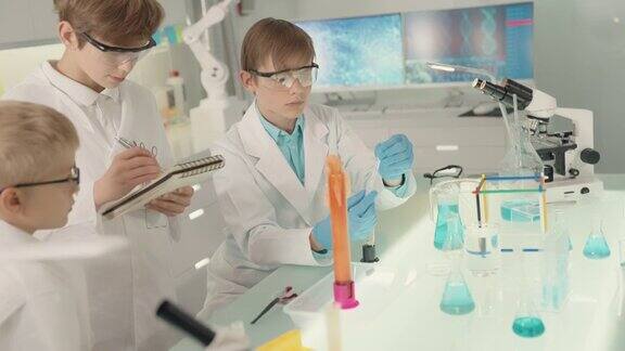 好奇的男孩在做科学实验实验室内部沸腾的泡沫液体