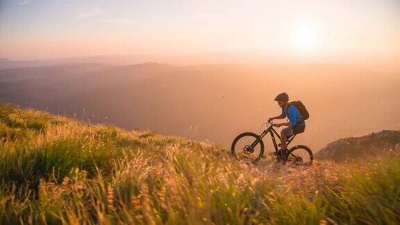 在大自然中做户外运动骑山地自行车上山在日落时被绿色的草地和山脉包围