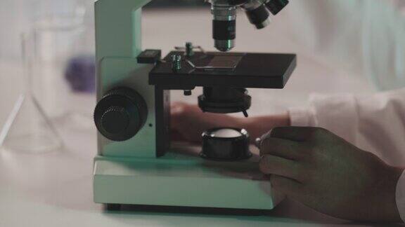 在显微镜下检查样品的科学家