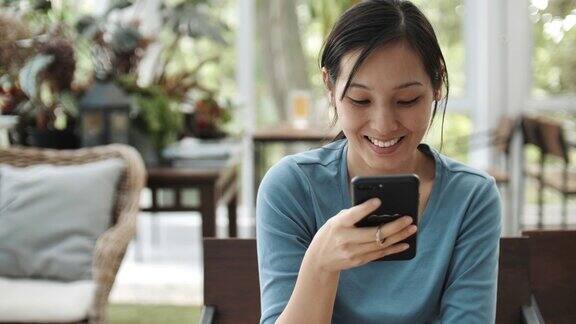 一个亚洲女孩在咖啡店的桌子上用智能手机上网