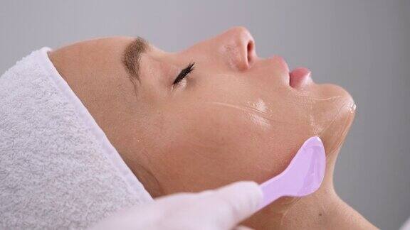 美容师把凝胶涂在病人脸上美容程序美容医学临床