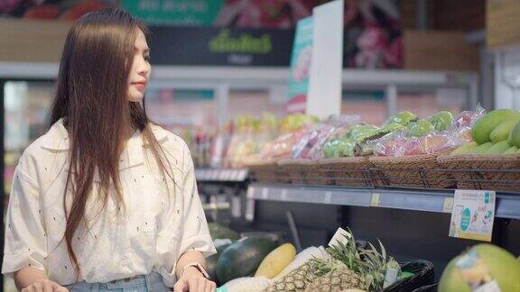 年轻的亚洲女子商店新鲜购买水果超市