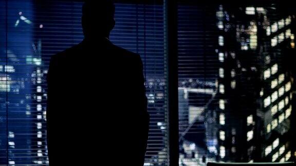 深夜商人站在他办公室的窗户前可以看到大城市的景色