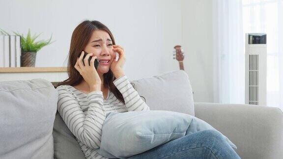 亚洲美女坐在沙发上在家里打电话快乐迷人的年轻女孩在家里度过休闲时光放松心情享受在客厅用智能手机交流和讨论