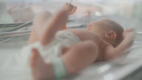 可爱的白人新生儿躺在妇产科医院的摇篮里一个小顽皮和精力充沛的孩子的肖像腿上有一个名字ID标签保健、怀孕和母亲概念