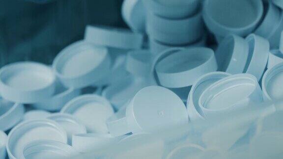很多白色的塑料帽工人的手捡起了一些医用膳食补充剂生产线制药工厂