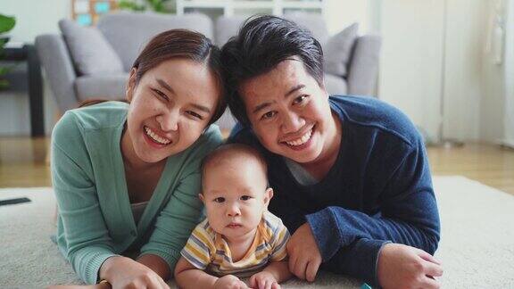 肖像幸福的亚洲家庭与婴儿躺在地板上微笑着看着相机