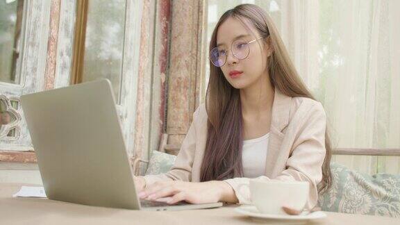 亚洲女性自由职业者使用笔记本电脑远程工作在联合工作空间咖啡馆