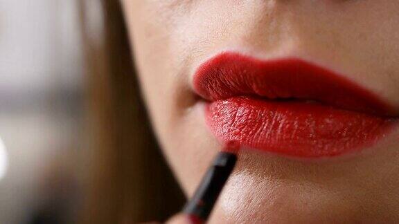 面部美容师用红色唇膏给女人涂嘴唇