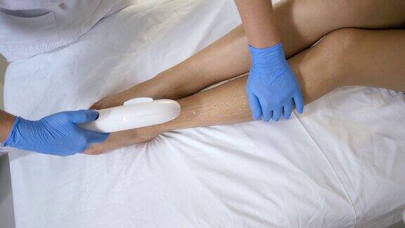 激光脱毛专业美容师在水疗沙龙治疗室用激光机为女性患者进行脚部脱毛