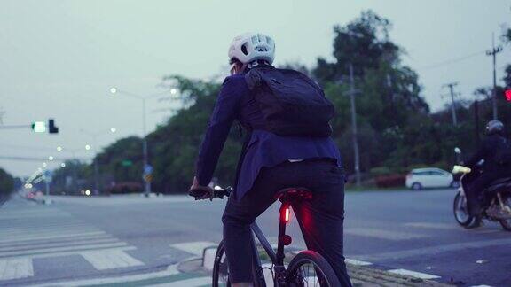 晚上下班后骑自行车回来的亚洲男人他在红绿灯前停了下来