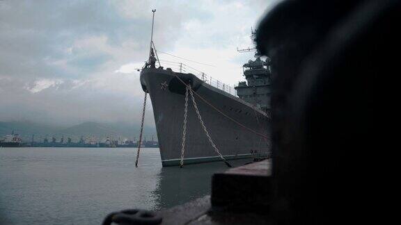 一艘巨大的军舰停泊在一个工业城市的港口