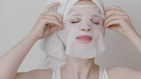 头戴白色毛巾的女人在脸上敷补水面膜