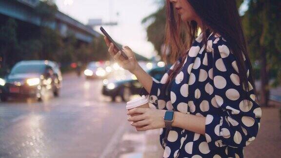 亚洲女商人晚上在城市街道上用智能手机发短信