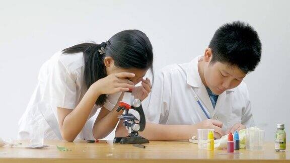 亚洲小学生穿着实验服一起在科学课上使用显微镜教育理念