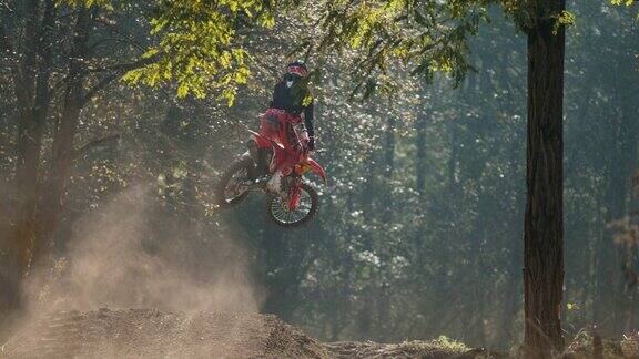 MS超级慢动作摩托车越野赛车手跳过土堆在阳光明媚的树林
