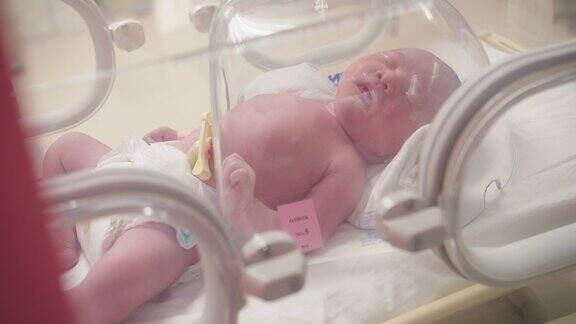 特写可爱的小新生儿躺在新生儿保温箱里出生后有呼吸问题的新生儿新生儿重症监护室的新生儿