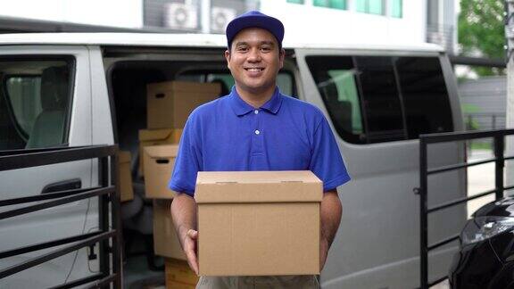 电晕病毒概念Smiley蓝色英俊的亚洲男子拿着包裹纸箱站在货车前面4k分辨率和慢动作拍摄