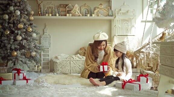 在圣诞节的时候微笑的母亲和女儿玩圣诞礼物的红丝带