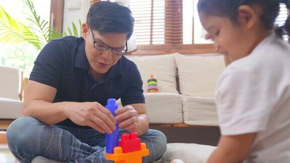 4K亚洲父亲和小女儿在家里玩积木玩具