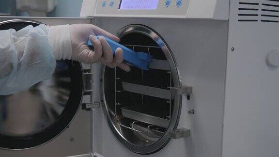 医务人员从高压灭菌器中取出装有特殊包装的无菌仪器这种设备对于用过的手术器械的灭菌是必要的