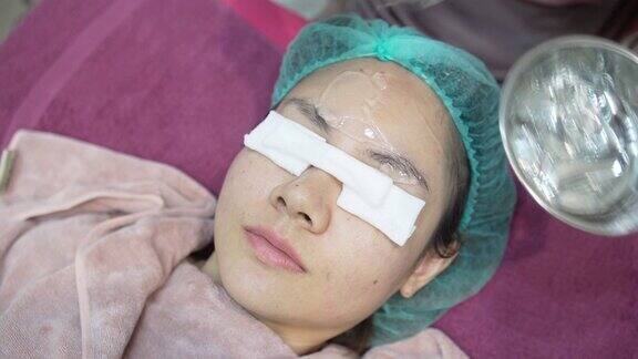 护士在一位亚洲妇女的脸上涂了一种透明的凝胶在美容诊所医疗和美容皮肤科预约概念