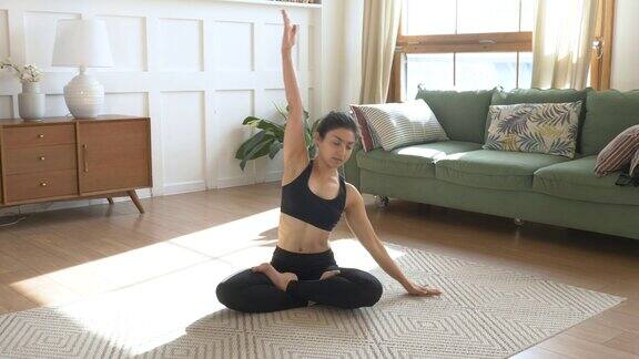 运动印度女人在家做伸展运动没有瑜伽垫黑色运动服灯光房间在家里早上