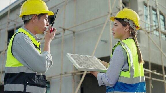 亚女工程师咨询安装太阳能电池板利用可持续资源在房屋与工头在建设村庄项目发展项目利用可持续资源