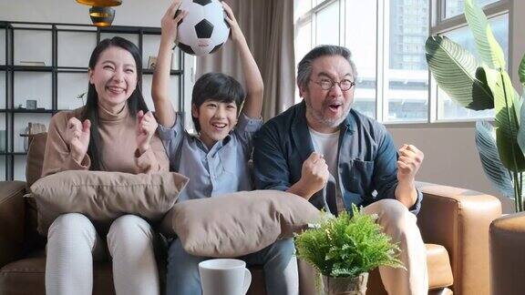 亚洲家庭在电视上观看足球比赛当球队把球射进球门时他们高兴地激动起来
