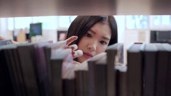 亚洲女学生在一所大学图书馆找书和取书教育