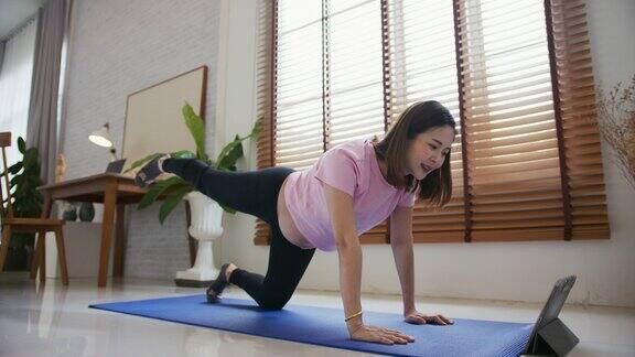 孕妇一边做瑜伽一边看在线辅导课