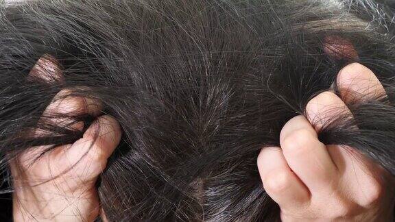 担心难过的女人中年妇女摸着她的黑色头发和灰色的发根近距离