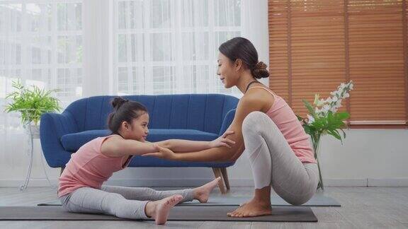 母亲正在家里教女儿伸展身体瑜伽锻炼