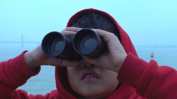 小男孩惊讶地在游船上用双筒望远镜看