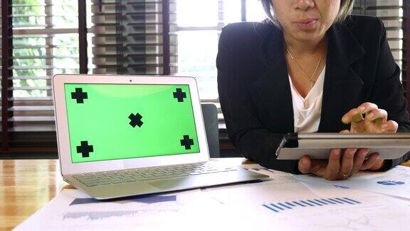 商业女性使用数字平板电脑和笔记本电脑绿色屏幕