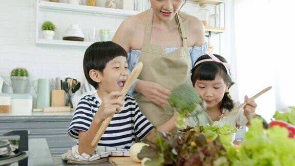 快乐的亚洲家庭在家里的厨房里做饭一起享受家庭活动