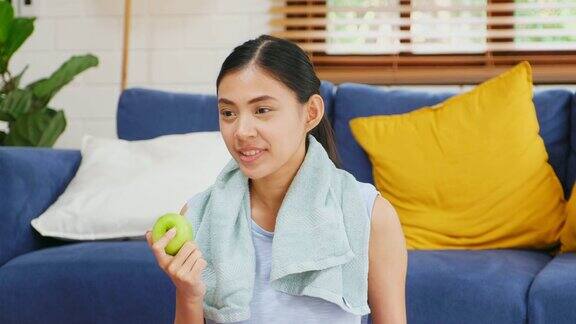 年轻的亚洲女子吃青苹果后在家客厅锻炼人与健康的生活方式幸福