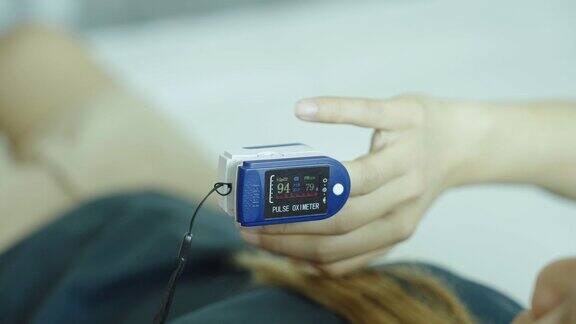 年轻的亚洲妇女自我测试血氧计检查她的血压和心率