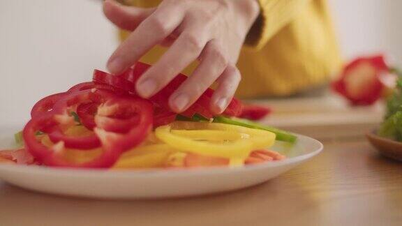 特写的一个女人在一块木板上切辣椒和甜椒蔬菜准备食物做沙拉在家里的厨房