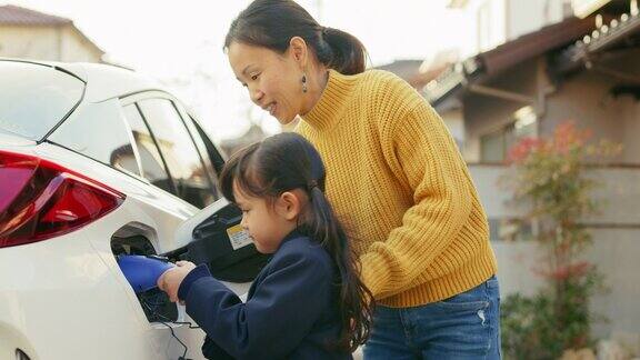 小女孩在家帮妈妈给电动汽车充电